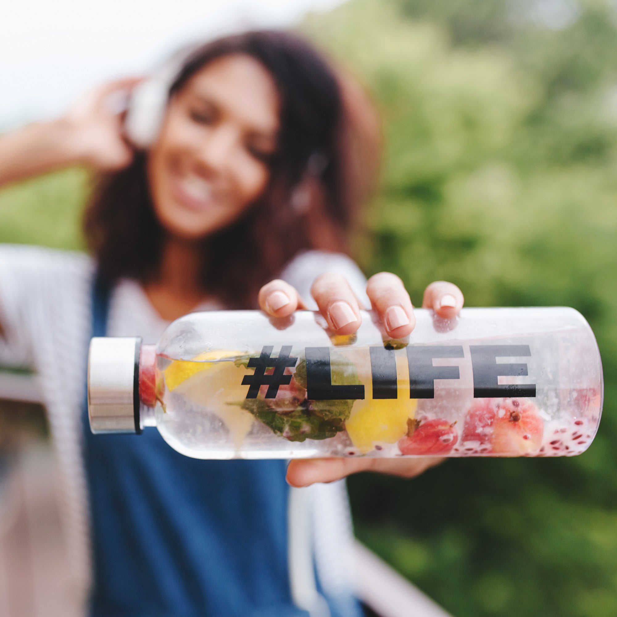 outdoor-portrait-smiling-black-girl-white-shirt-with-bottle-her-hand-foreground - SOS Hydration-sa