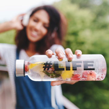 outdoor-portrait-smiling-black-girl-white-shirt-with-bottle-her-hand-foreground - SOS Hydration-sa